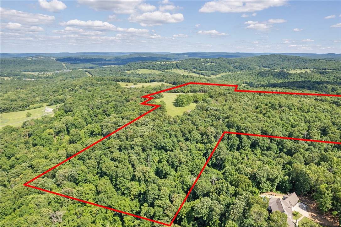 Escape to the serenity of Smokey Bear Rd, where 80 acres of pristine natural beauty await. This rare offering includes four contiguous parcels featuring a breathtaking mix of rolling hills, mature hardwoods, rocky bluffs, and expansive views of the Boston Mountainsāall just under 10 miles from downtown Fayetteville and Dickson Street. This private and secluded retreat is teeming with native wildlife, including deer and turkey, and offers multiple potential building sites, making it ideal for a family compound, weekend getaway or luxury estate. One homesite has already been prepared with a water tap and meter in place, perc test completed, Ozarks Electric and Ozarks Go on site and a cleared driveway with access from paved roadāready for future construction. A spring-fed wet weather creek weaves through the landscape, adding to the propertyās rustic charm and natural appeal. Whether you're looking to build, explore or invest, this stunning property combines the best of privacy, accessibility and untamed Ozark beauty.