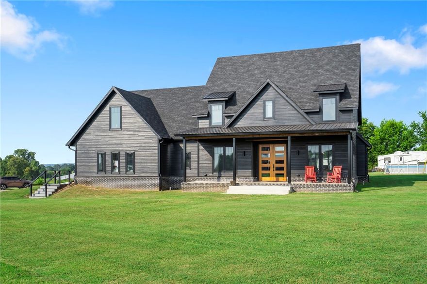 Nestled on 4.64 acres, this striking home blends modern craftsmanship with thoughtful design. Inside, an open floor plan and soaring ceilings create an inviting flow, anchored by a gas fireplace with a stunning 10 1/2 foot solid walnut hearth. The Chef's kitchen boasts custom cabinetry with specialized inserts, stainless steel smart appliances, and plenty of workspace. Upstairs, a loft-style game room overlooks the main living area and opens to a second-floor balcony through a unique garage-style door. The homes solid steel support posts, 14-foot glass double sliding doors, and 8-foot Mahogany front doors speak to both strength and style. A wired bar sound and hidden safe room add functionality and peace of mind. The outdoor space offers a large shop with 500sq.ft.of covered porch space, perfect for hobbies, storage, or projects. Whether hosting friends or savoring quiet evenings, this property offers a unique blend of comfort, security, and modern luxury!