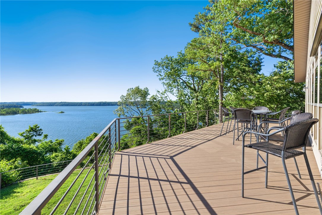 Absolutely breathtaking sunset views of Beaver Lake! Step inside to the open main level with hickory wood floors and plantation shutters that create a warm and inviting home. The gourmet kitchen flows seamlessly into the living and dining areas with attached office space and access to a spacious wrap-around composite deck - ideal for soaking in the panoramic lake views year round. The primary suite features private deck access, ample closet space, and a large en-suite bath. The walk-out basement includes a large living area, rock fireplace, wet bar, two additional bedrooms, a full bath, and a versatile bonus room. With spray foam insulation, Low-E windows, and a durable rock and Hardie board exterior, this home is efficient and elegant. Oversized 2-car garage with expanded parking and pull-through driveway. Located just 15 minutes to Downtown Rogers and 4 miles to Prairie Creek, this home is perfect as a primary residence, vacation retreat or short-term rental.