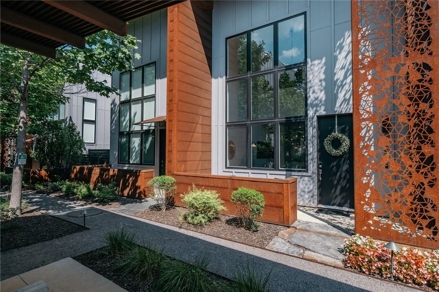 Welcome to the "Market District Loft", an elegant 3-story condo in the Tourmaline Lofts near The  Momentary in Bentonville. This modern urban retreat, bathed in natural light, offers a perfect blend of style and comfort. The open living area, with high ceilings and large windows, is ideal for relaxing or entertaining. The fully-equipped chef's kitchen and high-end dining area set the stage for memorable meals. Enjoy the convenience of a private garage and unwind on your serene patio. The main floor includes a half bathroom, while upstairs, the primary bedroom features a unique peek-a-boo window with ensuite bathroom and 2 additional bedrooms that share a well-appointed bathroom with a tub-shower combo. A third-floor office space provides a quiet retreat for business or relaxation, surrounded by captivating art from local photographer Ed Cooley. Just steps away, immerse yourself in Bentonville's dynamic scene with easy access to The Momentary, Meteor Cafe, Blu Sushi, 8th St Market, and more.