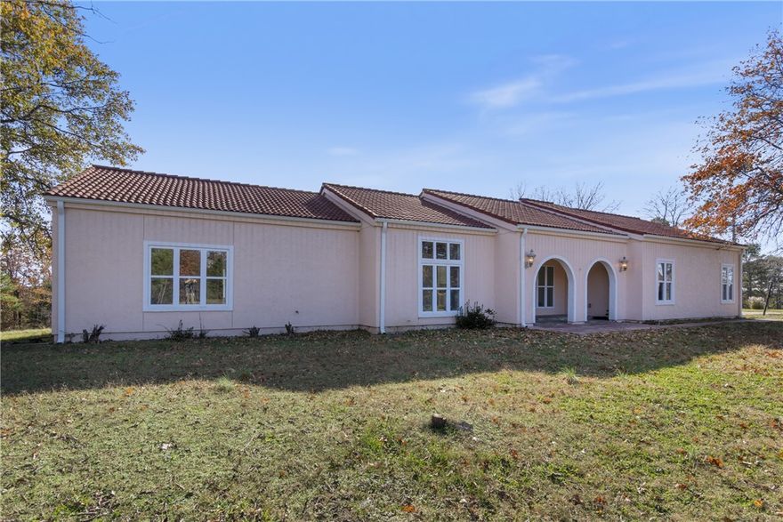 Escape to your own private retreat just minutes from town! This beautifully remodeled 4-bedroom, 2-bath Mediterranean-style home offers 2,143 sq ft of updated living space on 4.12 secluded acres. Renovated top to bottom in 2025, it features soaring ceilings, fresh paint, new flooring, modern lighting, and elegant designer finishes throughout. The stunning kitchen boasts quartz countertops, soft-close cabinetry, and a formal dining area ideal for gatherings. Each bathroom has new vanities with quartz countertops and backlit mirrors. Enjoy an open-concept family room with an electric fireplace or unwind in the luxurious primary suite with a Jetta Jacuzzi tub, rain shower, and huge walk-in closet. The oversized 2-car garage includes a workspace area. A charming 10x14 outbuilding with porch adds versatility for storage, hobbies, or a studio. Move-in ready and perfectly blending country charm with modern luxury—your peaceful escape awaits!