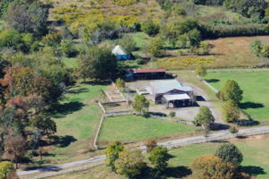 The custom block masonry drive through barn with steel trusses. 9 total horse stalls. 1 stud stall, with run partially covered, 4 inside stalls & 4 outside covered stalls . Inside stalls have built in hay racks and feeders and are plumbed for automatic waters. There is 420 sq ft of living quarters that consist of an efficiency apartment complete with kitchen, bathroom and H&A unit. There are 2 roll up doors that allow you extra convenience for storage, or tractor parking. Tack Room has concrete floor and saddle racks. There is a tool room or extra storage area, wash bay with hot water heater and dryer hookups. Hay lofts on both sides above stalls. New roof 2015. 4 dog kennels with runs partly covered that drain into a septic tank. Mineral rights do not convey.