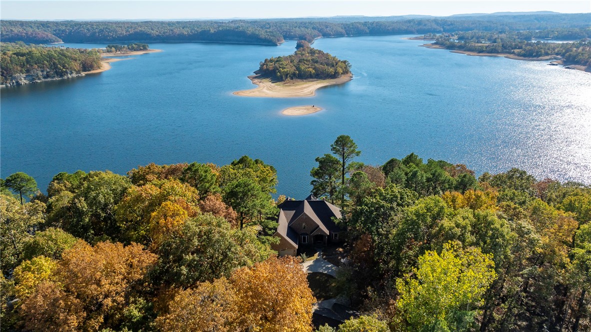 Perched on top of Devils Head Bluff this 3.67 AC of serene lakefront home offers an unbeatable million-dollar view of Horseshoe Bend on Beaver Lake. With 4,751 sqft of beautifully designed space, it features 4 bedrooms & 3.5 bathrooms, blending luxury and comfort. The open living room, flooded with natural light from Pella windows w/ built-in blinds, showcases the breathtaking lake scenery. The main floor includes a spacious kitchen, office, utility room, & half bath, while the primary suite offers a peaceful retreat with lake views. Step outside to the expansive deck, as you soak in the beauty of nature & the stunning lake views. Walkout basement perfect for entertaining, w/ a second living room, wet bar, bedroom, full bath, & bonus room. The third floor includes 2 bedrooms, full bath, & extra storage. Outside, a gated entry leads to a circular drive & detached two-car garage, each equipped w/ 220-watt outlets for electric vehicles. W/ new roof in 2024, this home is ready to offer lakefront living at its finest.
