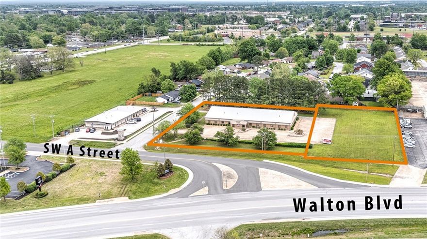 Prime commercial property located at one of Bentonville’s most visible and active interchanges: SW A Street and S Walton Blvd. Offering unmatched exposure in a highly desirable corridor, this 10,209 square foot office building is just one mile from downtown Bentonville. This listing includes two parcels totaling 1.92 acres. The 1.09-acre parcel includes a steel frame building, while the adjacent 0.83-acre lot allows for flexibility to expand your footprint or additional development. Whether you’re planning retail, office, mixed-use, or something entirely unique, this site offers rare potential in a fast-growing area surrounded by strong businesses and ongoing development. Opportunities like this are becoming harder to find in Bentonville—don’t miss your chance to create something standout in a city that continues to grow and thrive.