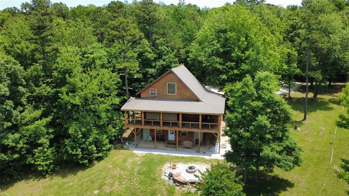 Rustic-style home featuring a covered front porch with lattice railing, a sloped metal roof, and wood siding
