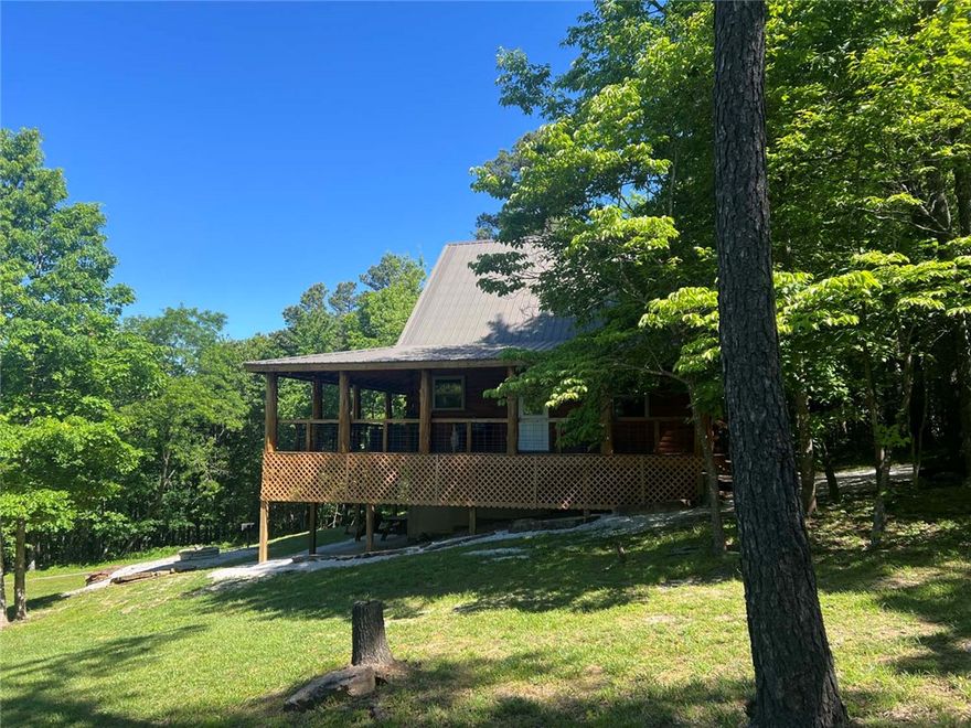 Located in the scenic Ozark Mountains in Jasper, Arkansas, this spacious cedar log cabin offers the perfect combination of comfort, privacy, and adventure. Surrounded by beautiful hardwood trees and peaceful mountain views, the property is conveniently located near hiking trails, abundant wildlife, and the breathtaking Buffalo National River.
Offering nearly 2,000 square feet of living space, the cabin features 3 bedrooms plus a large open loft designed to accommodate multiple beds. Outside, the wraparound porch provides the perfect setting for outdoor grilling, entertaining, or simply sipping coffee while enjoying the peaceful mountain scenery and fresh Ozark air.
Currently operating as a successful nightly rental, this turnkey property comes fully furnished with all contents conveying, making it ready for immediate use as an income-producing investment, vacation getaway, or full-time residence.