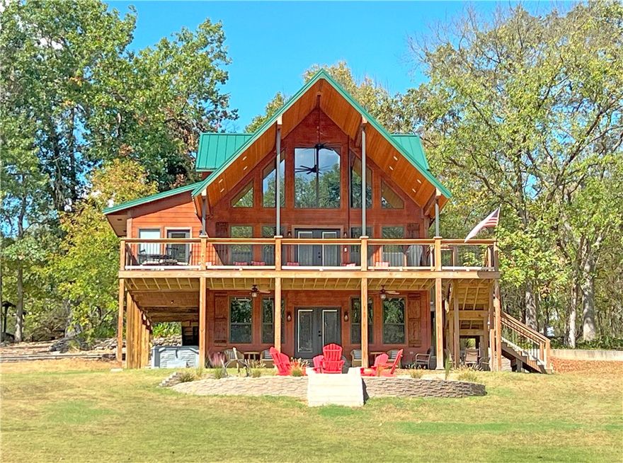 Peaceful refuge w/scenic views of the White River, one of the most beautiful retreats w/ river access between Beaver Lake & Table Rock. LAUNCH YOUR BOAT FROM THE RIVER FRONT ACCESS, FISH THE RIVER OR CRISE TO TABLE ROCK LAKE. This lodge combines rustic charm w/ modern comforts. Featuring cathedral wood ceilings, an open floor plan, a river rock fireplace, the signature red canoe lighting feature & a master bedroom ensuite. French doors lead to an expansive covered deck ideal for outdoor grilling with ample seating, overlooking the landscape and river.
Upstairs, a loft includes a custom entertainment nook, two uniquely furnished bedrooms w/ artisan-crafted reclaimed oak bunk beds, and a full bath. The walkout basement offers a bedroom, full bath, extra storage, a safe room, and a second living area, with access to an outdoor fire pit and saltwater hot tub. Near the river, enjoy an outdoor pavilion  w/a kitchenette, bath, and seating area, plus an additional secure space for vehicles and equipment. Ask 4 Updates PDF