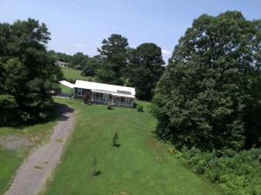 Custom cabin style home with 1 bedroom and 1 bathroom on 5.75 acres. The custom living space has a cathedral style open living area. Living Room has a wood stove that sits on granite tile with a floor to ceiling brick enclosure. Kitchen offers custom cabinets by James Pendergraft and an island with an eating bar. The bathroom includes a ceramic tile shower with corner bench and ceramic tile floors.  The bedroom offer to closets and a barn style door. There is also a sunroom, where you will probably spend most of your time, unless you are enjoying one of the many decks or porches. 2 car metal carport with concrete slab, (2) 20 x 20 metal storage buildings,(one is concrete, one has a wood floor) 2 Green houses, and 4 raised garden beds in a fenced area, and also a RV Electrical hookup.