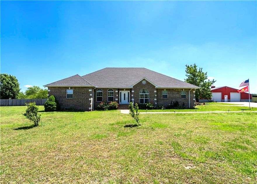 Beautiful custom brick home on 5.7 acres just minutes from town! A concrete drive leads past newly planted pecan, apple, peach & plum trees to the home & 60x60 shop. Offering 3,144 sq ft, this home features 3 bedrooms, 3.5 baths—each bedroom with a private bath—plus a large office with built-ins, a music/game room or 2nd office, & a second living area or 4th bedroom. Semi-open, split bd floor plan. Kitchen includes granite, an island workspace, gas range, double wall ovens, & huge pantry with garage access. Sewing room off the oversized utility room. Oversized bedrooms with walk-in closets. Hand-scraped hardwood & tile flooring. In-line propane water heater(6-yr). In-ground saltwater pool (4-yr liner, 2-yr cover) in privacy-fenced yard. Brick 10x16 storm shelter with electric. Shop includes 20x25 lean-to & 1,200 sq ft 1 bed/1 bath apartment-ideal for multi-generational living, in-law quarters, guests, or rental income. 17 mi to U of A in Fayetteville, 9 mi to Siloam Springs, & 15 mi to​​‌​​​​‌​‌​​​‌‌​​​‌‌‌​​‌​​‌‌​​​​ I-49.