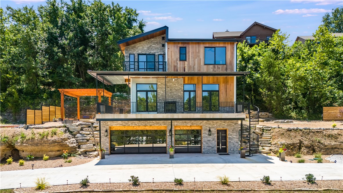 From the builder & mastermind of the creative Tree House in Bentonville we proudly present the Cliff House. We can't wait for you to see this stunning new construction perched on a cliff, offering breathtaking views of Beaver Lake from every room! This exceptional home sits on .53 acres & features 3 beds, 3 baths & a full basement w/ a bonus room. Designed to showcase the incredible lake views, the open concept living area is complete with custom tile work, a floating metal staircase, and a chef’s kitchen. Enjoy the seamless transition between indoor & outdoor spaces with a see-through fireplace & a full deck that takes full advantage of the lake panorama. The covered deck, two patios & custom stone firepit create the perfect atmosphere for outdoor entertaining. The highlight? A wine/cigar room with a vault door and exposed cave, styled rock wall & custom wine rack. With a geothermal system and meticulous craftsmanship throughout.