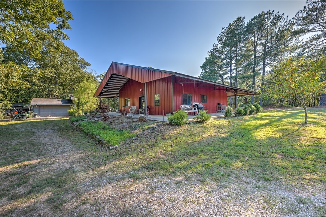 Nestled on approximately 20 acres of secluded woodland, this custom home embodies a harmonious blend of modern aesthetics and rustic charm. Its thoughtful design showcases concrete floors, reclaimed wood adorning walls and ceilings, and industrial elements such as corrugated features, track doors, and distinctive sinks and lighting fixtures. The open floor plan seamlessly integrates with a loft space, offering flexibility for conversion into additional bedrooms. The exterior boasts an all-metal finish, complemented by an expansive wrap-around covered patio, providing a perfect vantage point to appreciate the serene surroundings. Outside, a generously sized fenced garden, flourishing fruit trees, and a well-appointed chicken coop with a run enhance the property's homely appeal. Adding functionality are two large workshops, contributing to the property's allure as a haven that seamlessly merges modern living with nature's tranquility. Wildlife abounds, with turkeys, bears, and deer gracing the land.