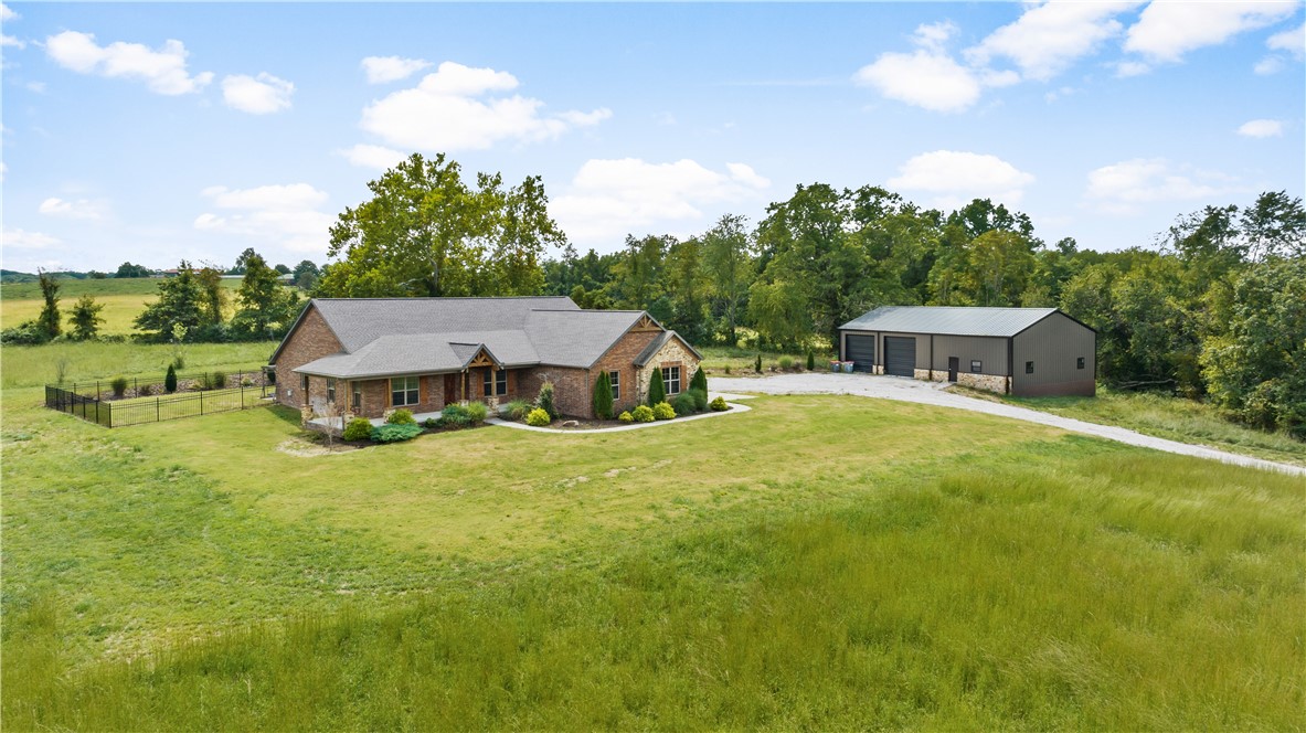 Welcome to your dream home on acreage! This like new 2018 built home on 9.36 acres of pristine land is sure to impress with its included 2,400 sqft detached shop for all your vehicles or toys! Boasting an expansive open floor plan interior with soaring cathedral ceilings and wood detailing, a stone fireplace, wood flooring, and plenty of natural light streaming in - this home has it all! The breathtaking eat-in kitchen features granite countertops, gas range, double oven, and an oversized island that is perfect for entertaining. Enjoy your morning coffee on the large covered front porch or unwind after work on the spacious covered back patio. Retreat to the relaxing primary suite with its spa-like ensuite bathroom featuring a soaking tub, tiled shower, his & hers vanities and roomy walk-in closet with plenty of built in storage. Also there is a "safe room" in the Master closet. Don't miss out on this one of a kind countryside escape today!