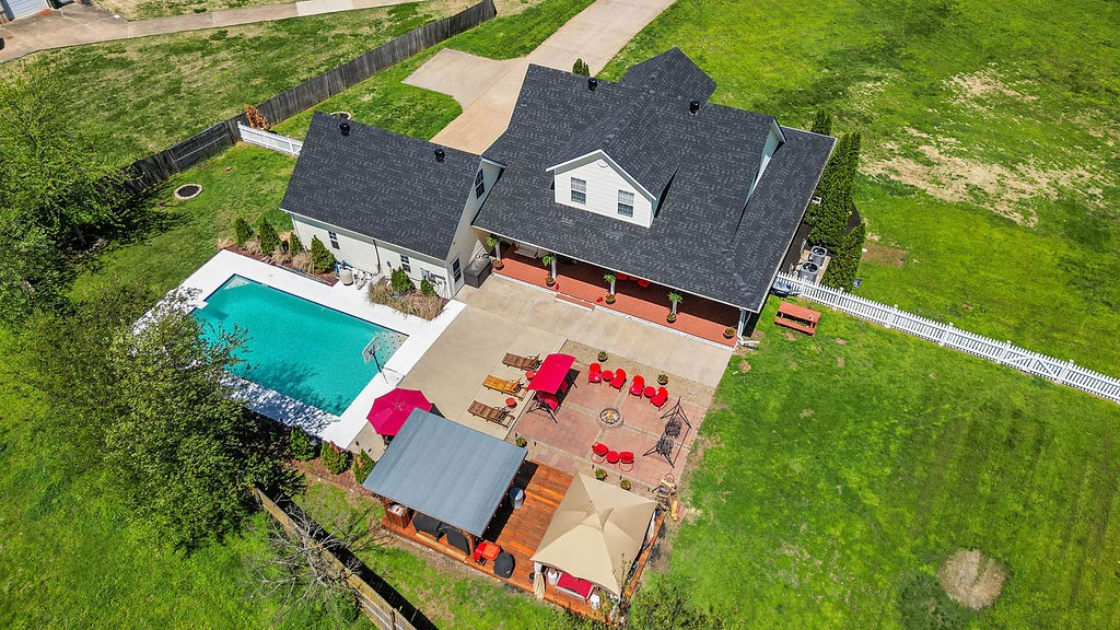 LOCATION! 1.13 acres with a Captivating 3 BR, 2.5 BA farmhouse-style home with an inviting wrap-around porch with white picket fence. There is an attached 2 car garage with Heated/cooled bonus room upstairs. Step inside the home to find natural light, warm finishes and thoughtful details throughout. Features include stainless steel appliances in the kitchen, Pellet stove in the living room, formal dining room & a Media room upstairs. Enjoy the peaceful outdoor setting from the porch or the large backyard which features a bar area w/Built in TV, plus a new canopy to relax in the shade. This backyard oasis is perfect for gatherings, gardening, or enjoying the sunset. Pool parties and sitting around the fire pit makes for a great night of fun. Plenty of room for pets and play. Detached 30x30 Garage/Workshop gives you options for either parking, storage or a hobby. Located in a quiet, scenic area, this home offers the best of country charm and convenience. Welcome Home!