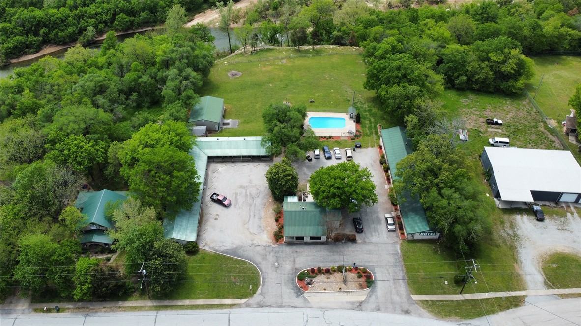 Move to the Ozarks and own your own business all in one location. This resort sits overlooking Crooked Creek and the pastures and hillsides surrounding it. This 18-room resort is on 2.7 acres with a residence and office on the property. The pool takes advantage of the panoramic views of the Crooked Creek with a fire pit situated just a few feet away. Very back of the property sits over the rapids on the creek and seller is working on stairs to the water. Additional 30x40 insulated storage/garage with power could be converted to rec room area or whatever you choose. Right on Old Main St and across from the County Library location is everything. In town yet country feel with super clean rooms, two laundry/housekeeping areas and a turnkey set up. What are you waiting on, your business and vacation all in one awaits!