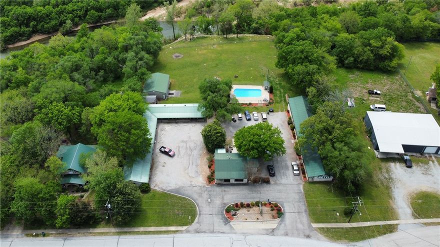 Move to the Ozarks and own your own business all in one location. This resort sits overlooking Crooked Creek and the pastures and hillsides surrounding it.  This 18-room resort is on 2.7 acres with a residence and office on the property. The pool takes advantage of the panoramic views of the Crooked Creek with a fire pit situated just a few feet away. Very back of the property sits over the rapids on the creek and seller is working on stairs to the water. Additional 30x40 insulated storage/garage with power could be converted to rec room area or whatever you choose. Right on Old Main St and across from the County Library location is everything. In town yet country feel with super clean rooms, two laundry/housekeeping areas and a turnkey set up. What are you waiting on, your business and vacation all in one awaits!