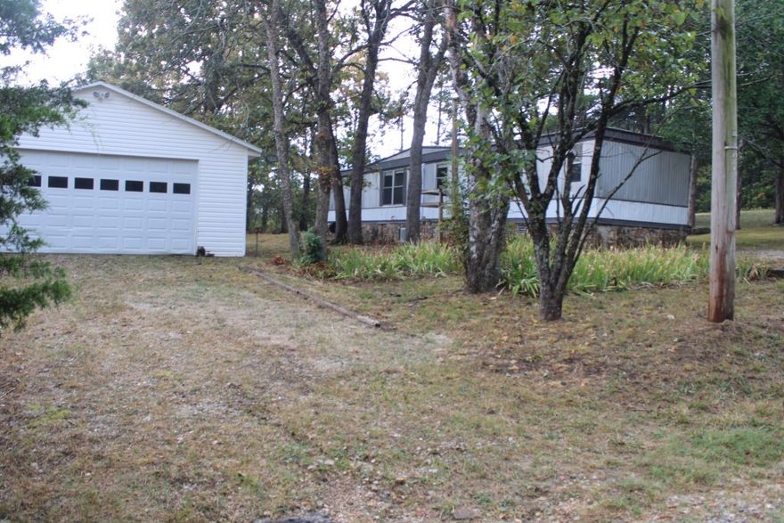 Bull Shoals Lake Get-A-Way - Home Plus 24 x 36 ft Garage / Shop Building - great for boat storage, workshop or both. Includes 2 bed/ 2 bath manufactured home, split bedroom plan, living - dining - kitchen combo with vaulted ceiling, rear deck with ramp for easy access, new mini split system, new interior paint, new roof coating Plus a 24 x 36 ft detached garage with vinyl siding, metal roof, concrete floor & electricity. Home connected to public water and sewer, plus water & sewer are beside the garage in case you want to add a bath or efficiency apartment inside the garage. Sits on 2 lots with shade trees only a few minutes north to Lake Bull Shoals with Corp of Engineers maintained park, marina, and public boat launch or a few minutes to south to 18-hole golf course. Shopping, post office, and bank only a few miles away, about 30 minutes to Harrison or 40 minutes to Branson, MO. Come See - Make this your get-a-way place or permanent residence.