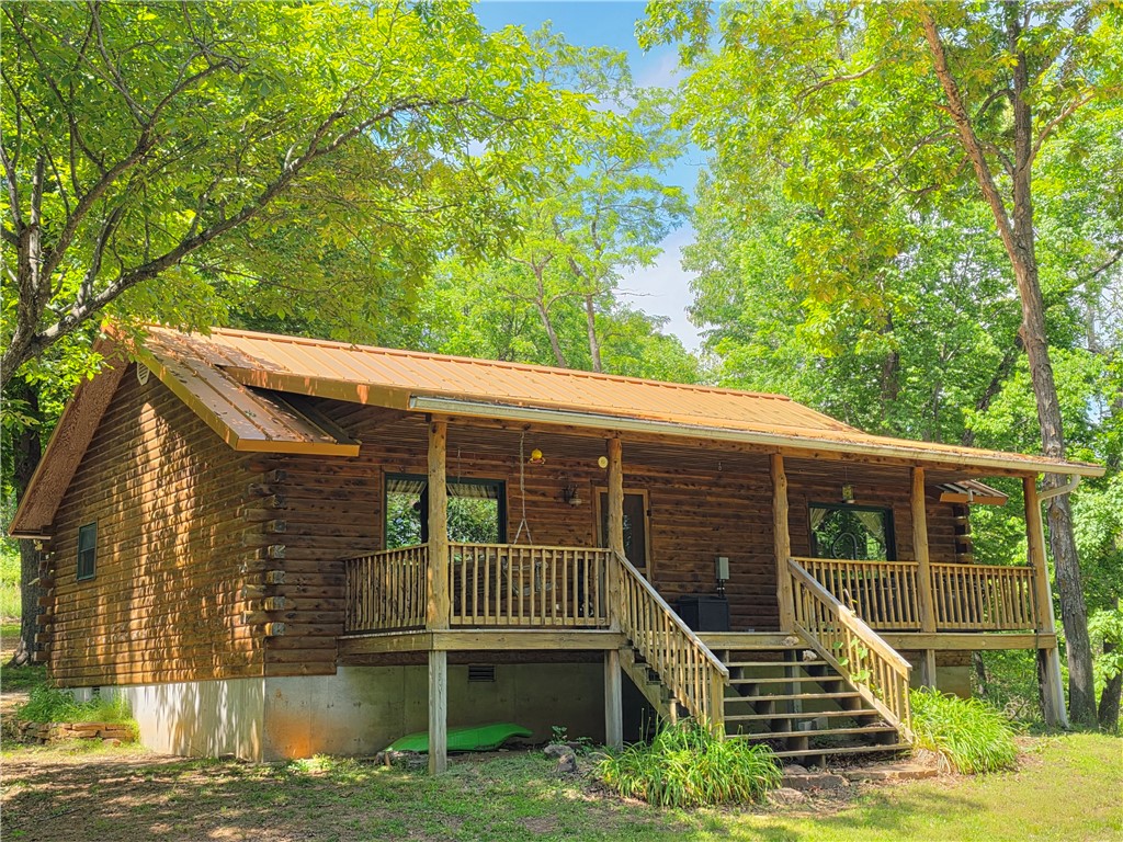Escape to this stunning 2BR/1.5BA cedar log cabin, nestled on 3 +/- private acres in one of the most sought-after areas of the Upper Buffalo River region. With its Western Red Cedar interior, hardwood floors and unique construction, this home is full of rustic charm and character, offering a peaceful & secluded retreat. Relax on the large covered front porch, complete with a porch swing and hot tub, or fire up the grill on the new 12x20 back deck for a peaceful evening under the stars. The fully equipped kitchen conveys with a refrigerator, propane range, and washer/dryer, and the cabin includes quality window coverings and some furnishings. This cabin is currently producing income as a nightly rental on Airbnb. Located just 5 to 15 minutes from world-class hiking trails, the Buffalo River, mountain biking, ziplining, and the famous elk herds of Boxley Valley Historic District, this cabin is perfect for outdoor enthusiasts and those looking for a serene getaway. Located only a short 1.5 hour drive from NWA.