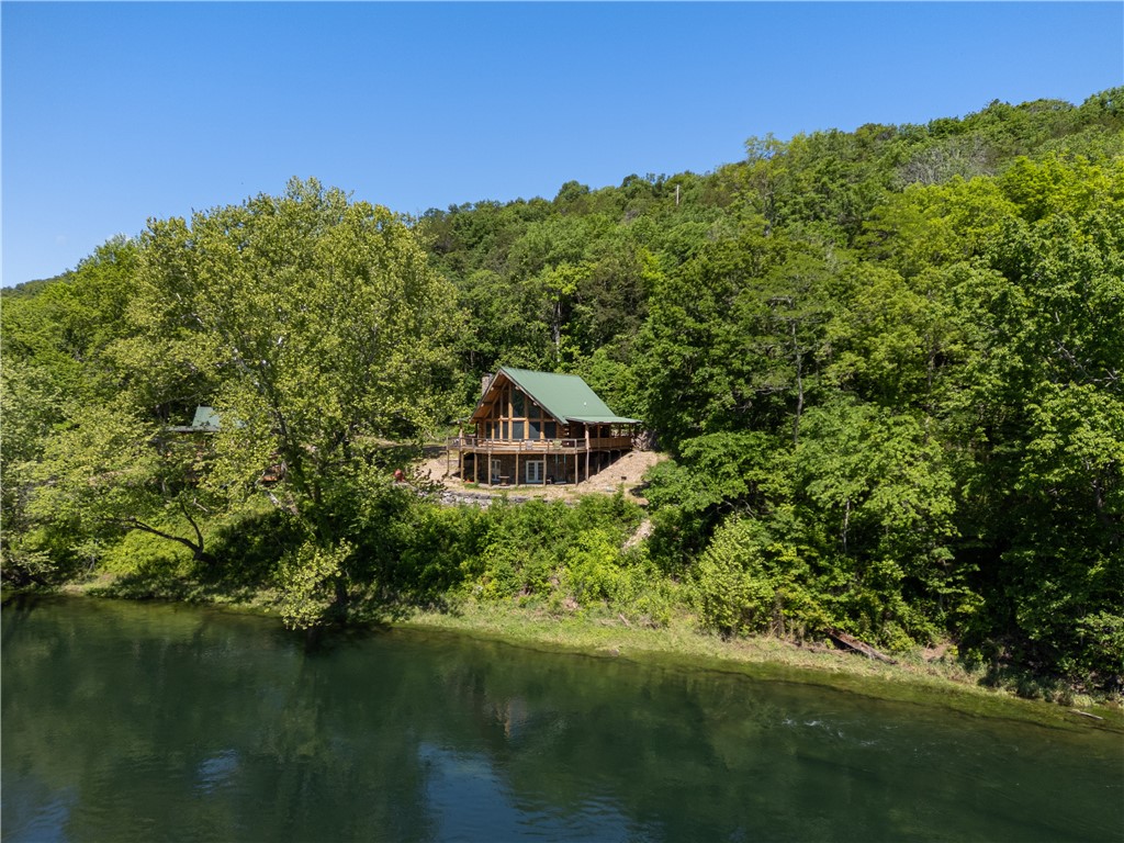 White River Waterfront Retreat! Situated on the banks of the White River below the Beaver Lake Dam, this 46-acre retreat offers privacy and solitude. Home to the Tailwater Club, it features a 2500 sq ft lodge with stunning views, easy water access, and only the sounds of nature. The 5bd/3ba Log Cabin Lodge boasts spacious rooms, a walkout basement, and a deck with downriver views. Accessible by county road or the adjacent state park, it's 30 minutes from Downtown Rogers, 20 minutes from Eureka Springs, 10 minutes from Mtn Bike Trails, and 5 minutes from Beaver Lake. Private guided tours are available by appointment. Please also see the 42+/- Land MLS# 1296438