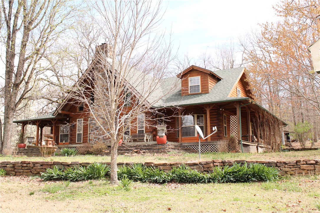 Custom log home with wrap around country porch! Private & peaceful on 2.3 wooded acres. Massive vaulted ceiling with native stone fireplace with wood burning insert. Master bedroom/bath & 2nd bedroom & bath on main level. 2 bedrooms - 2 baths on 2nd level with large 2nd living space/loft area with skylights. Nice kitchen. Part of wrap around porch is screened in. Large storage area off attached carport. Lots of rock work around the house. Great property! Great country living!