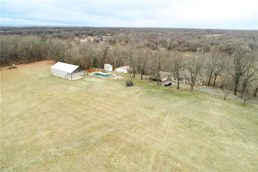 One fantastic home for the right family! This 21-acre spread has it all - a 3,278 SF home with 5 bedrooms and 4-1/2 baths, two family rooms (one upstairs, one down), an enormous new covered patio and wrap deck (936 SF), plus a 16x40 L-shaped heated inground pool (8.5 ft deep with a diving board), new flooring in the kitchen and family room, upgraded kitchen, plus lots of room to roam on the property. There are 3 tremendous shop buildings including a 2,400 SF fully insulated heated & cooled one with bathroom! Too much to mention here - you must see this one. View in back is remarkable!