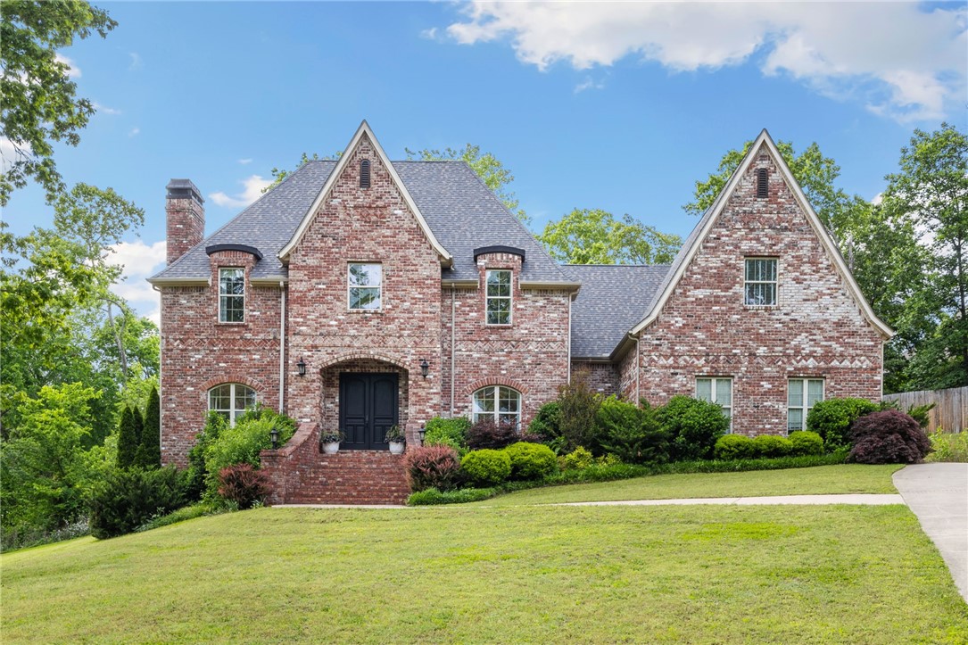 Discover unparalleled luxury in this stunning 5 bedroom, 4.5 bathroom brick estate spanning 5,681sq ft on 5.81 private wooded acres in prestigious Talamore neighborhood with Bentonville schools. This sophisticated residence features soaring coffered ceilings, rich hardwood floors, and custom millwork throughout. The gourmet kitchen showcases premium stainless appliances, black granite countertops & custom white cabinetry opening to bright living spaces with multiple fireplaces. Entertainment options abound with a professional home theater, wet bar with wine refrigerator & resort-style pool. Retreat to the primary suite with spa bathroom featuring large walk-in shower & bathtub. Additional highlights include built-in bookshelves, abundant natural light from oversized windows, multiple outdoor living areas & professional landscaping with stone accents. This extraordinary property perfectly balances elegant design & modern convenience in a tranquil setting while offering convenient access to Bentonville amenities.