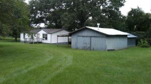 Interior paint in process.Laminate floors, metal underpinning, 2 decks, 2 year old roof, 2 shops and large trees. New lower price.Owner will consider owner financing.