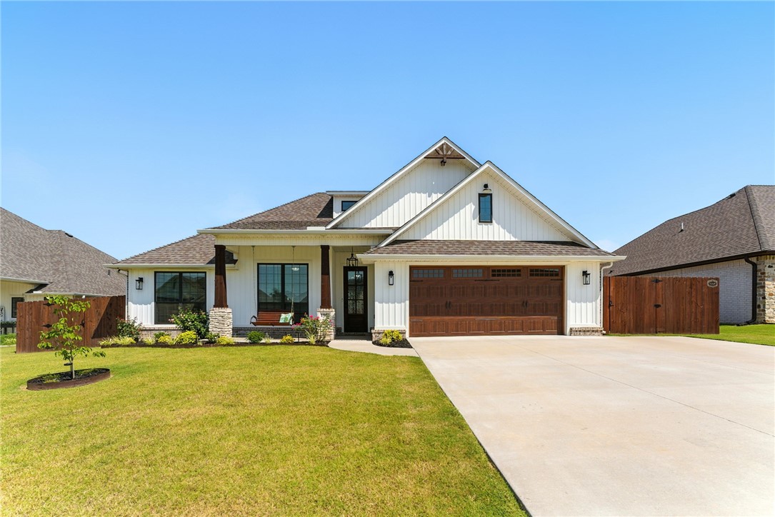 You'll fall in love with this 2022-built modern farmhouse. Step inside the gorgeous front door opening to a meticulously kept home with wood-like tile floors, carpeted bedrooms, crown molding, shiplap accents, and soaring ceilings that fill the space with light. The inviting living area boasts a cozy fireplace, while the kitchen showcases beautiful cabinets, energy efficient appliances, and a generous dining space overlooking the custom landscaped backyard. The primary suite offers a relaxing retreat with a soaking tub and walk-in shower and his and hers vanities. Outside, enjoy the welcoming front porch with swing, or entertain guests on the extended back patio with a fire pit, a lovely yard and well-maintained privacy fence. Located in desirable Elkhorn Subdivision, each home is unique, neighbors are friendly, and Walmart drones deliver. With Bentonville, Rogers, and Bella Vista 15 minutes away, this home perfectly balances charm, convenience, and community.
