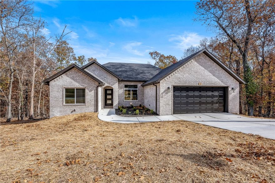 Construction is complete! Make this new build by Elite Thomas Homes your next home. Conveniently located on Bella Vista’s east side just off Lancashire/340 and less than a mile from the Back 40 Trailhead, this home offers a perfect blend of traditional design and natural surroundings.
Inside, you’ll find 3 bedrooms, 2 bathrooms, a dedicated office, and an oversized 2-car garage. The main living area features 11’ ceilings, a stacked-stone vent-free gas fireplace, and hardwood floors throughout the entry, living room, hallway, and primary suite. The primary suite includes a luxurious bathroom with a dual vanity and a spacious tiled shower with dual shower heads.
The two additional bedrooms and the office feature plush carpeting for comfort. The back deck overlooks wooded common property—no neighbors behind you, and both side lots are currently vacant.