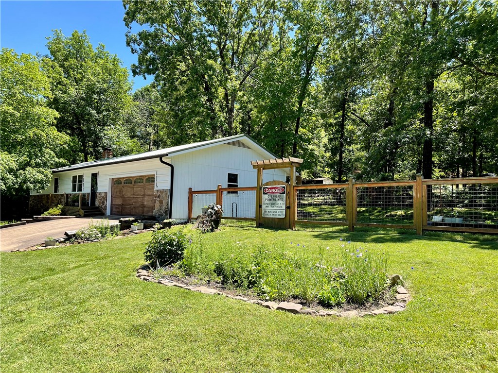 This impressive 3 bedroom, 2 bathroom property boasts a wood burning fireplace insert, a private fenced backyard complete with a soothing water feature. Home has updated windows, new kitchen cabinets, new retaining wall with drain, new flooring & paint, new vanity in primary, primary closet remodeled, new grass & topsoil. Home sold as is. Nice corner lot. Benefiting from a highly convenient location near local amenities and a short drive from Hwy 412, ensuring easy travel throughout NW AR making this a great location!