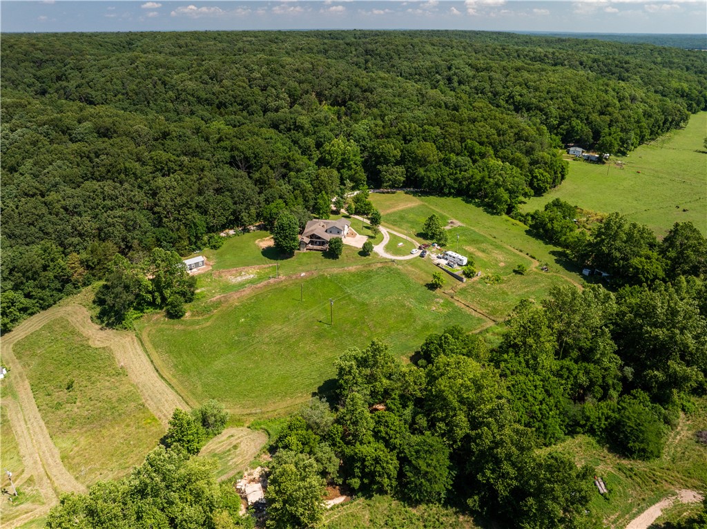 Do you need lots of space in the country and enjoy entertaining? This spacious home on 5 beautiful acres could be yours. Oh, and there's a creek at the bottom of the hill and gorgeous views. There are over 3,000 sq. ft. of living space. There are two primary suites. One is on the main level and one on the second level. Family room has skylights for added brightness and a pellet stove to warm those cold nights. The kitchen is spacious and comes with a gas range. Adjoining the kitchen is a bright sunroom. But wait, the massive covered patio with outdoor kitchen is ready for outdoor entertaining. Have a business from home with a large office space. Off the patio is a spiral staircase leading to a spare room that would make a great playroom. A tiny home with kitchen, living, bedroom and bath are included for your guests who will be wanting to join you in the peaceful country. Roof is 8 years old, new water heater in 2023, 40k HVAC system in 2022. Dogs will be put up for showings but they are very friendly.