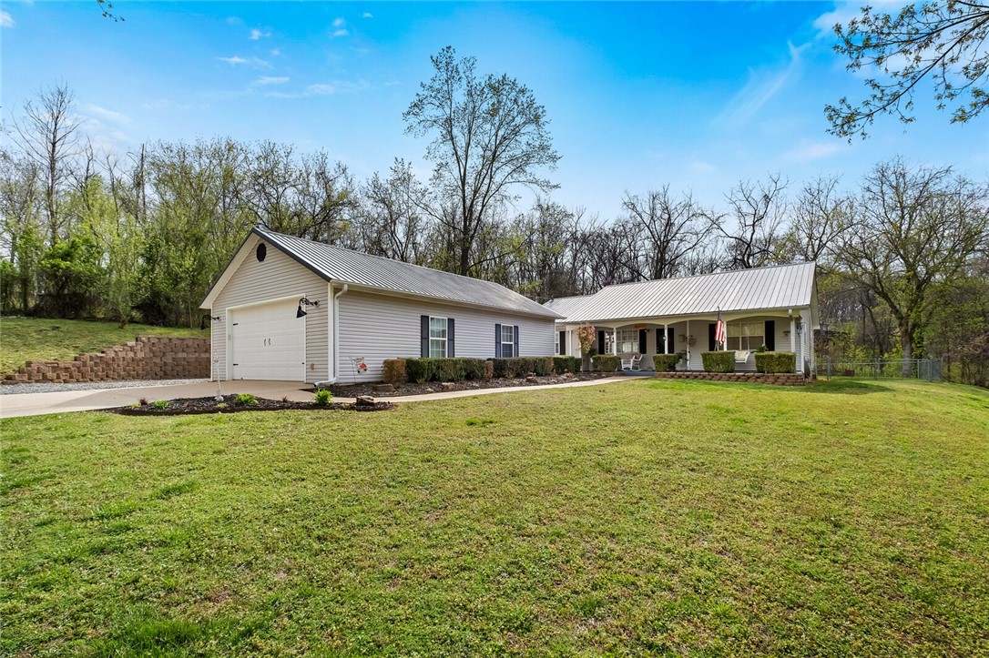 Recently remodeled home in a beautiful country setting on 2.75 acres, which includes two lots. Property has a natural spring and wet weather creek and is just 5 minutes from downtown Rogers. Home has a master suite with a oversized walk-in closet. The master closet could easily be converted back to a 3rd bedroom. Bright open split floor plan. Kitchen and bathroom features plank wood countertops. Kitchen has a deep farmhouse sink and Kohler oil-rubbed bronze faucet, large pantry and a "appliance garage" off of the laundry room. Loads of storage in this home with plank style wood look ceramic tile through-out. New water heater and HVAC system. Extra large detached two-car garage with attached bonus room that is heated and cooled. Could easily be converted back to a four car garage/workshop. Concrete slab to the left of home measuring 10 X 11 with septic lines run ready to build that second bathroom. Includes plank style wood look ceramic tile flooring for second bathroom.