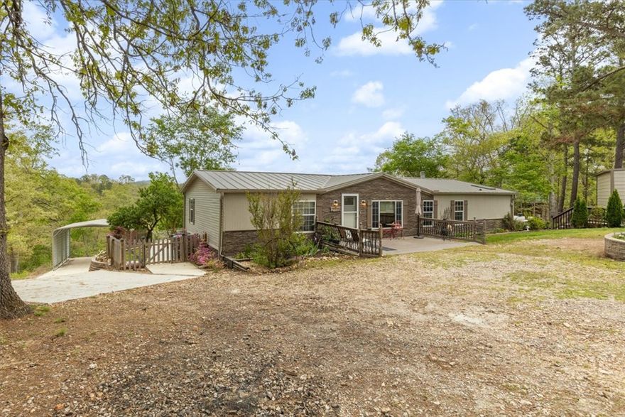 Charming and well cared for manufactured home nestled on 1.6 acres near Beaver Lake and only a 20-minute drive to Downtown Rogers! Enjoy quiet surroundings with room to spread out, plus a shop equipped with propane that is perfect for projects, an 8x10 shed for extra storage, and detached covered parking. The living room features a welcoming rock fireplace, creating a cozy focal point. The primary bath offers double sinks and a relaxing jetted tub. A front patio provides a warm welcome while the back deck is ideal for peaceful evenings or entertaining guests. A wonderful blend of comfort, space and location.