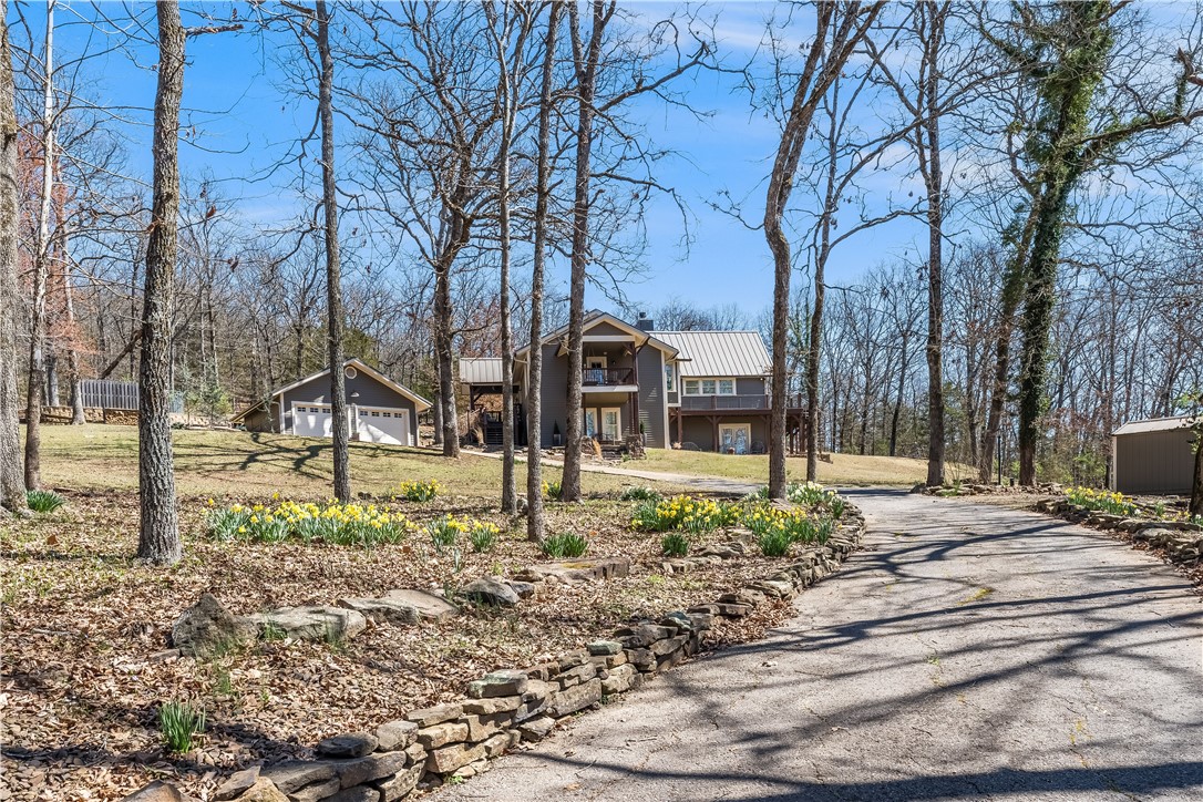 Best kept secret in town. 3620 sq ft home on 4.07 acres in east Fayetteville. SO many improvements: Metal Roof, Hardie plank siding, new garage doors, new upstairs HVAC, wood burning insert in LR, Pella windows in primary bdrm, extensive stonework in front & back patio steps, screens on gutters. Hardwood floors throughout, stunning upgrades. LR has wood burning insert, vaulted ceiling and wrap around windows, French doors to deck, breakfast room w/ granite table & built-in seating (table & bench convey), den can be a primary bedroom w/ bath, downstairs is incredible primary ensuite plus two more bedrooms & bath. The photos & virtual tour will help you visualize all the fabulous features of this home.