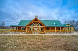 Custom built log home on 23 ac (+/-) with paved road frontage! You will love just how spacious this 5 BR 4 BA home is. Featuring windows, balconies, and porches everywhere you turn providing lots of natural light within the home as well as outdoor entertaining space. Double sided wood burning stone fireplace greets you on the large covered porch, and continues as you enter the great room. Amenities include hickory hardwood flooring, upgraded kitchen with huge island/bar with storage, quartz counters, double ovens and gas cooktop for the chef in the family; huge laundry/mud room area with great cabinets for storage. The master suite opens to the outdoors, and the master bath has a wonderful soaking tub with large walk-in shower.