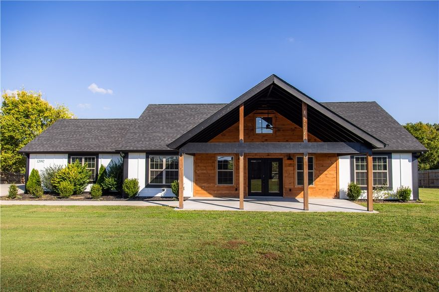 Welcome to 12092 Guyll Ridge Road, where rustic charm meets modern comfort. This beautiful, nearly new home features an open-concept layout with vaulted wood ceilings, luxury vinyl plank flooring, and a striking stone fireplace. The kitchen shines with quartz countertops, stainless appliances, rich cabinetry, and a warm wood island centerpiece. The primary suite offers a spa-like bath with dual vanities and a tiled shower. Enjoy mornings under the inviting front porch or evenings on the private back deck with scenic views on your one acre lot. Nestled just 10 minutes to Beaver Lake, 15 minutes to Downtown Rogers, and 25 minutes to Bentonville, this home offers convenient access to dining, shopping, and the region’s top employers while maintaining a quiet country feel. Move-in ready and beautifully finished, this is Northwest Arkansas living at its best.