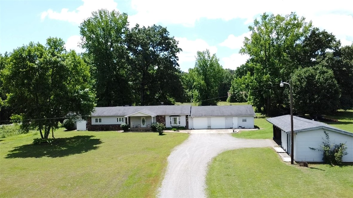 A little piece of country in the Mountain foothills. This beautiful custom built, 3 bedroom 2 bath home is nestled just as you begin the climb up into the Ozark Mountains. Home sits on 7.89 acres m/l with a park-like back yard where you can sit inside the screened porch, open deck or on a swing watching wildlife, while listening to a babbling stream with a footbridge crossing into a field containing a rustic barn. Home has a 2 car oversized garage, additional workshop, equipment shed, and storm shelter. The inside has an inviting fireplace, custom cabinetry, built in closet shelving, large walk in primary closet, alarm system and tons of storage thorough-out. New HVAC in 2024. New flooring throughout 2021. New roof 2022. Seller providing a Home Warranty.