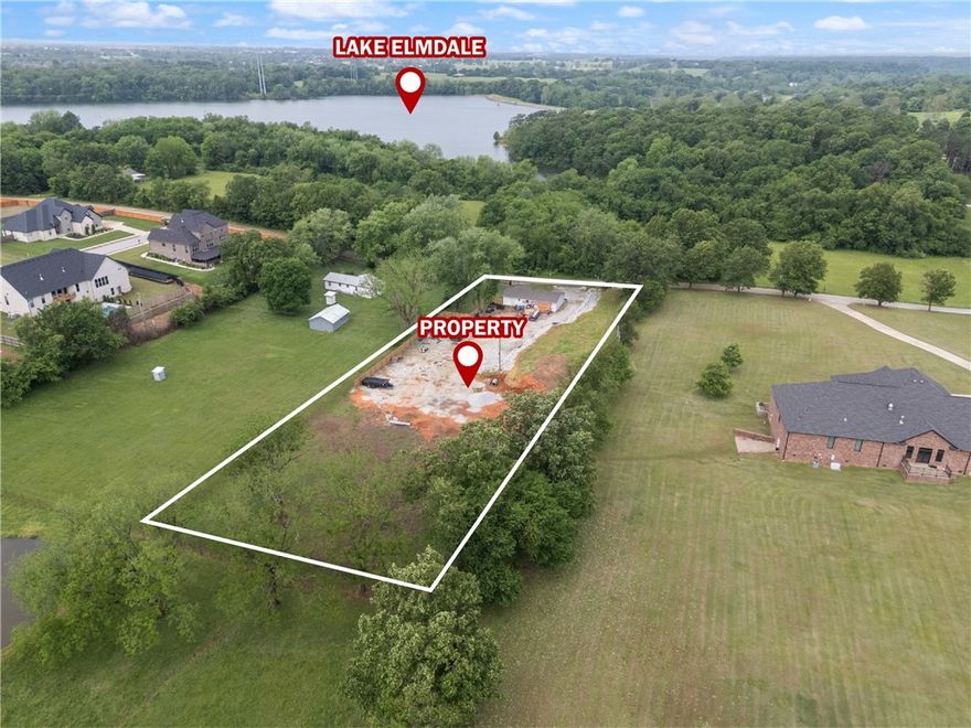 +/- 1.78 acres of level, partially fenced land in Elm Springs, AR and only a half mile from the Lake Elmdale Boat Ramp. Situated near the Elmdale Lake Estates, this property offers the perfect setting to build a custom residential estate-style home in a peaceful, scenic area. Lake Elmdale is a 200-acre no-wake lake known for excellent fishing opportunity, including largemouth bass, bream, catfish, and crappie. Conveniently located approx. 2 miles from Walmart Supercenter and I-49, 2.5 miles from Brush Creek Golf Course, and 3.1 miles from Har-Ber High School, this property offers the perfect balance of privacy and accessibility. Electric is on site with water and sewer available at the street - utilities are not currently connected. Don't miss your chance to own a beautiful piece of land near one of Northwest Arkansas's hidden gems. Home on site is sold as-is. No showings without an appointment, please do not walk the property without a confirmed appointment.