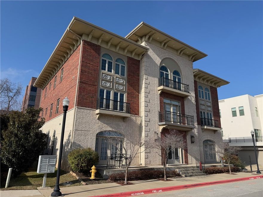 Located just two blocks from the Bentonville Square, American Flats stands as Downtown’s original condominium address—neo-classic in character and undeniably convenient. This ground-floor one-bedroom unit is open, bright, and designed for effortless living. The kitchen features custom cabinetry, granite countertops, and all-electric appliances. The bedroom accommodates a king bed with ease and connects to an Art Deco–inspired bath. Off-street parking is included. Make this your home base for walkable access to downtown’s boutiques, galleries, and standout restaurants.