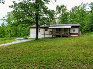 This is a beautiful piece of Ozark property. 19.33 acres facing Boat Mountain. The residence, is a mobile home with additional add-on living space totaling 1800 square feet. This includes living room with French doors to back deck, dining room/kitchen, 2 bed/1 bath with bonus room for music room or office and a large utility/ storage room. This property has well and city water. Plenty of wooded area for privacy and hunting. ADDED BONUS of cleared, level building site for future new home construction. This site offers priceless view and newly built, extremely secure safe/storm shelter. Seasonal creek run through property.Disclosure*Property currently will need a new septic system installed.