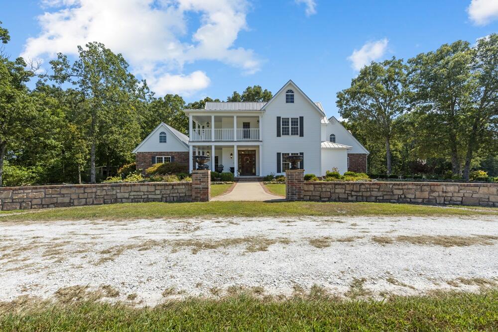 This elegant 4,400 sq ft farmhouse-style home sits on 21.5 acres with breathtaking Ozark Mountain views, just 5 miles from Harrison. Built 18 years ago, it's in pristine condition, offering 3-4 bedrooms (bonus room as a 4th), 2.5 baths, 2x6 walls, 9 ft ceilings, large windows, crown molding, and ash and hickory hardwood floors. The living room features a gas fireplace, while a wood stove warms the glassed-in sunroom. The eat-in kitchen is a chef's dream, with stainless steel appliances, Silestone quartz countertops, and a spacious pantry. The main level includes a formal dining room, den, and a luxurious master suite with an office, dual walk-in closets, and a modern bath with heated tile floors, a soaker tub, double vanities, and a walk-in shower.