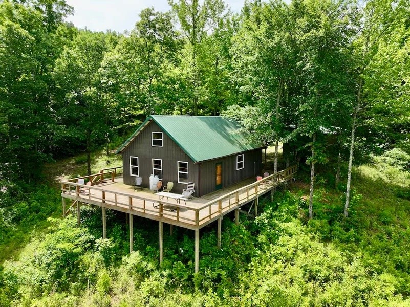 Off grid cabin on 60 acres with breathtaking views of the peaceful Ozark mountains that surround. Overlook the stocked pond from your custom built cabin with wrap around deck, kitchen, full bath, and loft area. Cabin features septic and spring fed well. The lean to shed is a perfect spot to park your toys. Plenty of trails on the property. Legal easement to property.