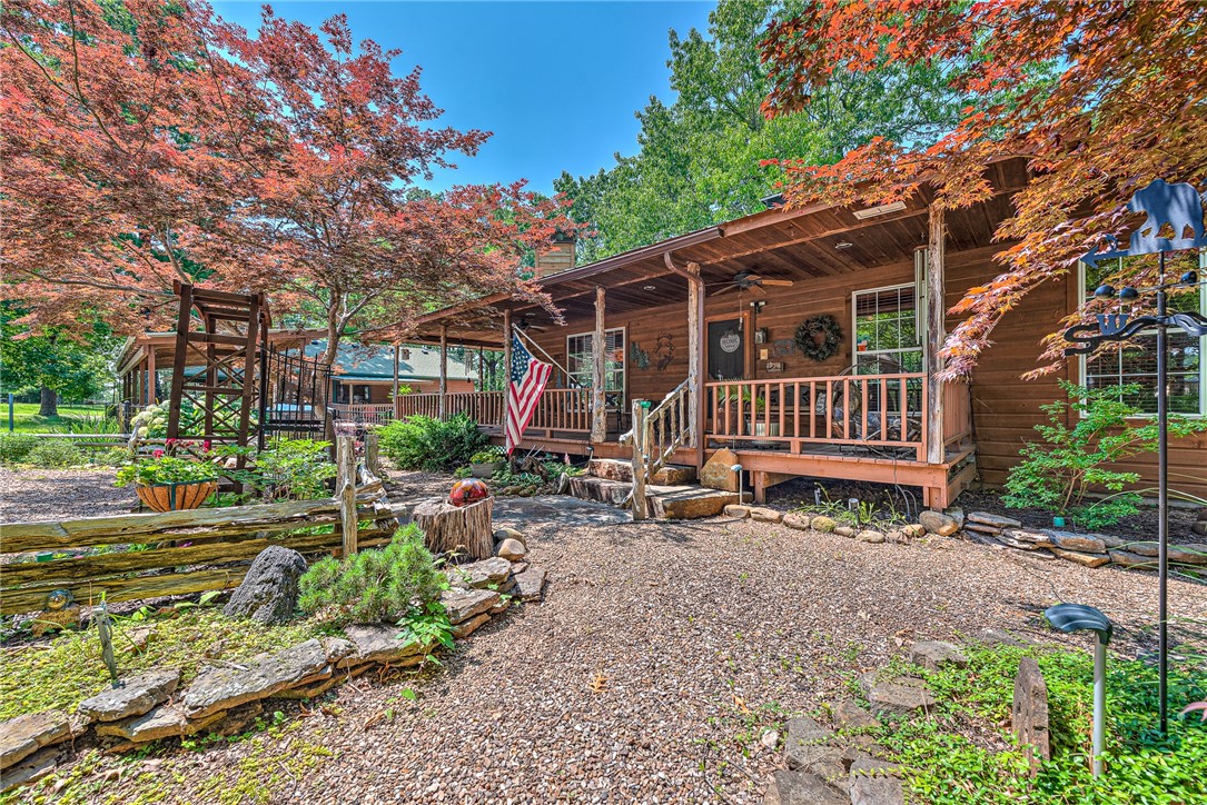 Escape to the rustic charm of this 2.78-acre lodge-style retreat near Beaver Lake’s Rocky Branch, featuring a 3,052 sq ft main home—including a downstairs pub—and a 790 sq ft guest house with a heated/cooled 790 sq ft shop. The main home showcases custom doors, built-ins, real antler chandeliers, and wood-burning fireplaces. Downstairs offers a cozy pub, full bath, and workshop—ideal for entertaining or hobbies. A spacious 4-car garage with an extra roll-up door provides ample storage, and a whole-home Generac generator ensures year-round peace of mind. The guest house/in-law suite includes pine floors, a full kitchen, and private patio for extended stays. The attached heated/cooled shop has a half bath and potential for additional living space. Outdoor amenities include a solar-heated sport pool, hot tub, plumbed outhouse, turfed bocce ball court, RV parking, and lush landscaping filled with perennials and native plants. This one-of-a-kind property blends comfort, craftsmanship, and outdoor luxury.