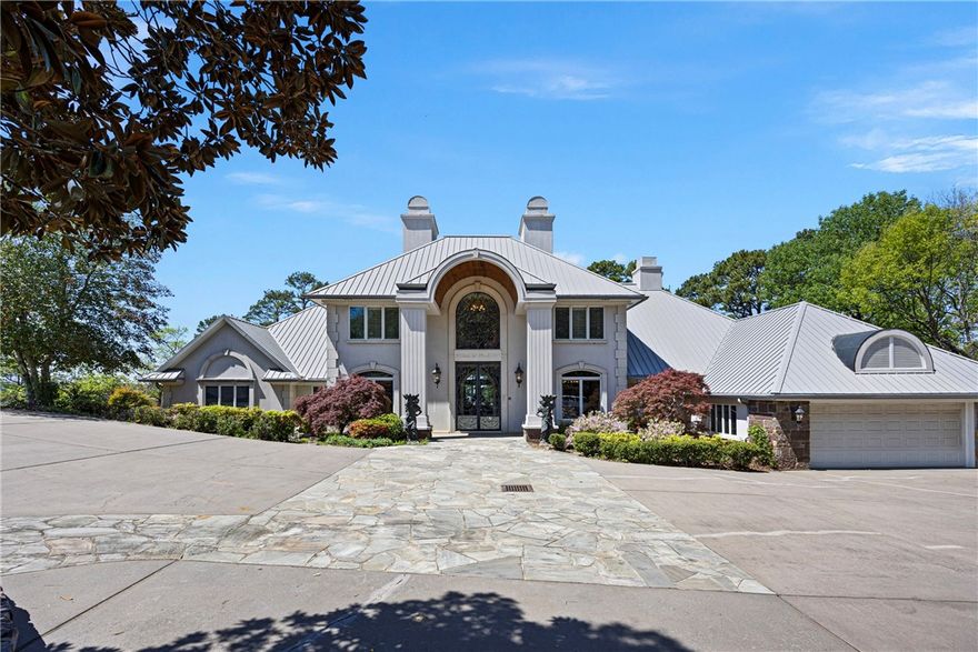 Renowned for its exclusivity and timeless stature, 1 Rim Rock Drive is truly in a category of one, surrounded by mature evergreens and hardwoods, concealed on its own end of a bluff. An iron security gate & towering iron doors set a tone of prominence for the entire property. This is amplified in the great room with heated marble floors, ornate columns, and floor-to-ceiling windows that introduce a remarkable view. This view can be taken in from the balcony, saltwater pool, and the rest of the manicured yard down to the bluff. Refined finishings and woodwork tastefully characterize the interior. The top level contains two bedrooms & their respective bathrooms. The main level consists of a great room, kitchen & pantry, lounge, dining area, living room, formal dining room, study, a guest suite, the master suite, and a half bathroom. The lower level is accessible by either an elevator from the lounge, or stairs, and serves as a spacious area to entertain, complete with a wet bar, full bathroom, and exterior doors.
