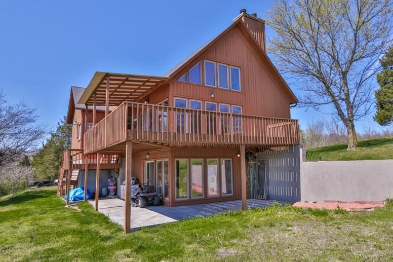 Newly remodeled custom cedar home on 2.5 acres in Hickory Creek—just 2 mins from Beaver Lake marina! Built with durable Steel I-beam construction, this home offers stunning views from every floor, floor-to-ceiling picture windows, and a wrap-around deck/patio. The open-concept main level features a 22-ft stacked quartz wood-burning fireplace connecting the living, kitchen, and dining areas. The master suite includes a walk-in closet and a luxurious marble walk-in shower with rain head. A second bedroom and bath feature custom tile and jetted tub. Upstairs, a rod-iron/wood staircase leads to a loft, third bedroom, and bath with a body jet shower. Walkout basement includes a stacked quartz fireplace, wet bar w/ sink, cooler & dishwasher, half bath, and storm shelter. Insulated 2-car garage has a built-in workshop. Outside: gazebo, fenced garden, fruit trees, and more. Too many high-end finishes to list—plus, many items convey!