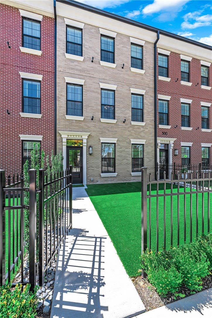 Rarely does a townhome deliver this level of detail. 1,200 pounds of hand-set cast stone frame the entry with dentil molding, fluted pilasters, and scroll corbels. Chevron hardwood flows through all three levels. The main level lives open: chef's kitchen with quartz sink, quartz waterfall island, GE Cafe range, vented Faber hood, and pot filler, flowing into a dining area and formal living room with wet bar for entertaining, every window framed by quartz sills. Custom 7-foot solid core doors and smart toilets with bidet features throughout. The primary suite features a walk-in closet and spa-like bathroom with floating vanity, backlit LED mirror, and Hansgrohe rain shower. Two generous secondary bedrooms each have attached baths. Private fenced courtyard. 2-car garage with epoxy floors and EV hookup. Walk to the Square. Adjacent to Gilmore Park and the new STEM university. Minutes from Crystal Bridges, the Momentary, and 8th St Market.