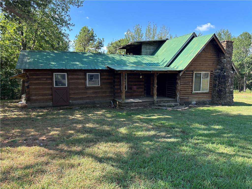 41.76 rolling acres of scenic Arkansas land featuring a rustic log cabin (approximately 1605 sq. ft. that’s divided into a studio living space (432 sq. ft. heated & cooled) on one side and a storage area (1173 sq. ft) on the other. The cabin sits tucked back from the road, offering peace, privacy, and immersion in nature. A fully fenced orchard (135’ x 85’) hosts a variety of 3-year-old fruit trees—including apple, peach, pear, plum, cherry, jujube, mayhaw, pawpaw, and mulberry—alongside rows of thornless blackberries, elderberries, and blueberries. Nearby, a fenced garden area (75’ x 50’) contains 12 raised beds for easy planting and maintenance, also protected by 6-foot woven wire fencing. The property includes several additional structures: a 40’ x 30’ garage ideal for storage or workshop use, a 15’ x 10’ greenhouse for extending the growing season, a 40’ x 15’ RV pole barn, a 30’ x 25’ smaller pole barn suitable for animals or tools, and a spray-foamed 25’ x 12’ well house with a 1,500-gallon holding tank