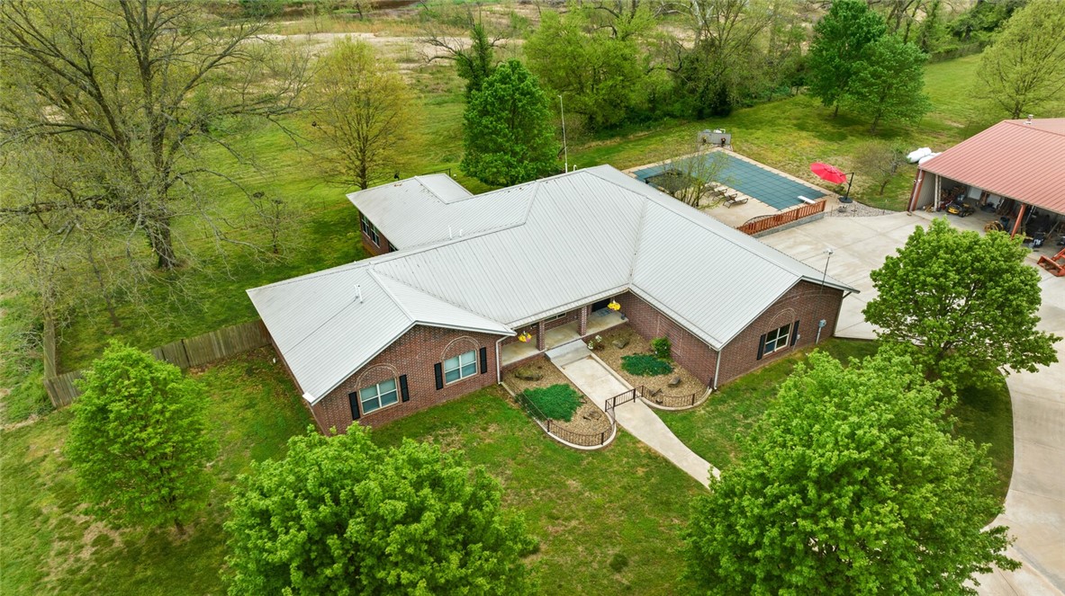 This amazing property is ideal for someone looking for a peaceful retreat while still only 20 minutes from Downtown Bentonville. The 3600 sqft all brick home features hardwood floors with tile in bathrooms, laundry and sun room, a split floor plan, 4 bedrooms, 2.5 baths, dedicated office, spacious kitchen with Corian counter tops, breakfast nook, formal dining room with built-ins, large living room with see through gas log fireplace, sunroom with views in every direction, an oversized 3 car garage, and sits on 15.96 acres! Cool off in Spavinaw creek which beautifully outlines the entire southern edge of the property or in the 30,000-gallon saltwater pool with new liner and filter on hot summer days. A heated 45x50 red iron metal building with 20x50 lean to, RV height garage door, 18x24 enclosed room, and 200 amp service provides ample space for all the toys and equipment you could need. House was built using all metal framing. Encapsulated attic and crawl space. Available without additional lots see MLS 1272881.