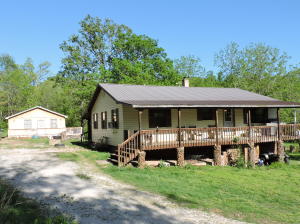 Two homes on 10 beautiful acres. 2 bedroom, 1 bath home with large living room. Large front & back porches, both covered. Unfinished basement. Hardwood floors. Newer cabinet doors & counter tops in kitchen. Brand new 1 bedroom, 1 bath cabin. Cedar exterior & metal roof. Deck on 2 sides. Nice metal barn plus a shop building. Older cabin used for storage. Huge garden spot. Food plot. 2 ponds. Seasonal creek.