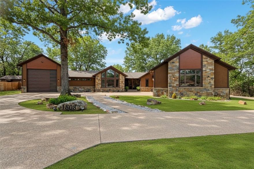 Breckenridge-inspired architecture meets Arkansas luxury in this unforgettable rock-and-cedar retreat with approx. 4,100 sq ft of interior living and 7,500+ sq ft under roof. A sweeping circular aggregate driveway leads to a dramatic stone-and-cedar façade with clean modern rooflines, blending mountain-lodge charm with upscale style. Inside, Control4 automation, Lutron smart switches, zoned audio, and Alexa-controlled Keego zebra shades make daily living effortless. The chef’s kitchen features a Jenn-Air 6+ burner range, solid cherry cabinetry, black granite counters, and a striking three-way gas fireplace shared with the dining area. The oversized primary suite offers a sitting area, sunny reading nook, spa-like bath with Jason Micro-silk tub, walk-in shower, dual vanities, and custom closet. Outdoors, enjoy a grotto pool, waterfall, stone terraces, and a covered king-truss patio with fireplace and outdoor kitchen stub-out. Garage space fits 7+ vehicles, including a 50+ ft RV bay.