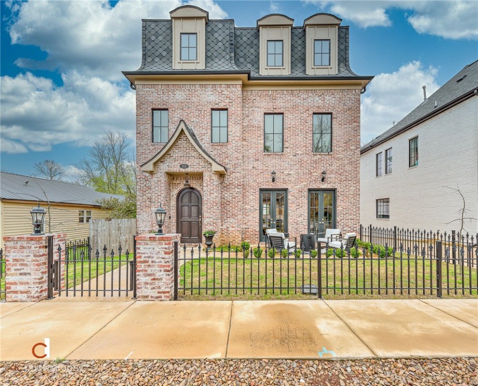 You can't beat life on Main Street in Bentonville! You will LOVE this custom, 3 story, European style home with income producing carriage house (additional 714 sq. ft). It boasts vintage brick inside and out, high end lighting (Anthropologie/Restoration Hardware), floor to ceiling tile in the kitchen, Quartz/Quartzite countertops, wood clad windows, upgraded shingles, custom iron gate, courtyard, covered back porch, bonus room, office, private alley, and separate garage. Home is only 2 blocks from the trails, .7 miles to ice cream at Spark, a short bike ride to the 8th St. Market, and you can sit on your back porch in the summer and listen to the outdoor concerts at Crystal Bridges. Studio style carriage house includes quartz countertops, high end tile, and luxury vinyl plank flooring - pictures available upon request. Too many upgrades to list. This house is one of a kind. Your dream home awaits! Agent owned.